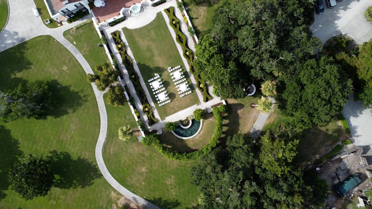 Drone view of a wedding ceremony set on the lawn of a formal garden estate