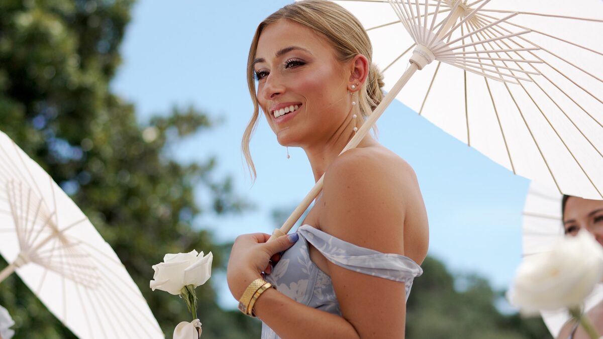 Bridesmaid holding a white paper parasol in bright sun, a still from a wedding film
