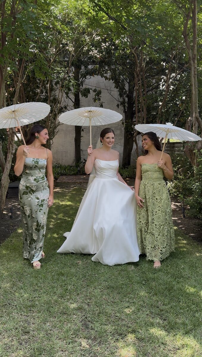 Bride walking with two bridesmaids under paper parasols, an iPhone content creation frame