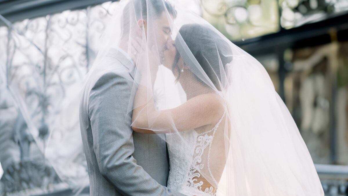 Bride and groom kissing beneath her veil