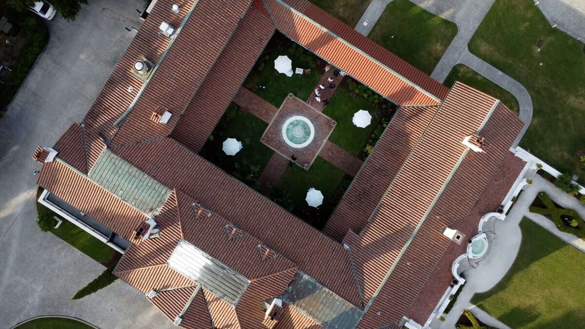 Drone view of a courtyard wedding reception with a red tile roof