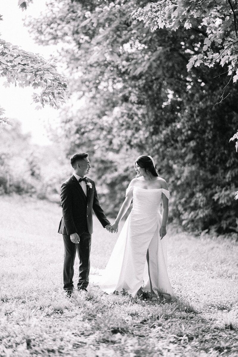 Black and white: the couple walking hand in hand beneath the trees