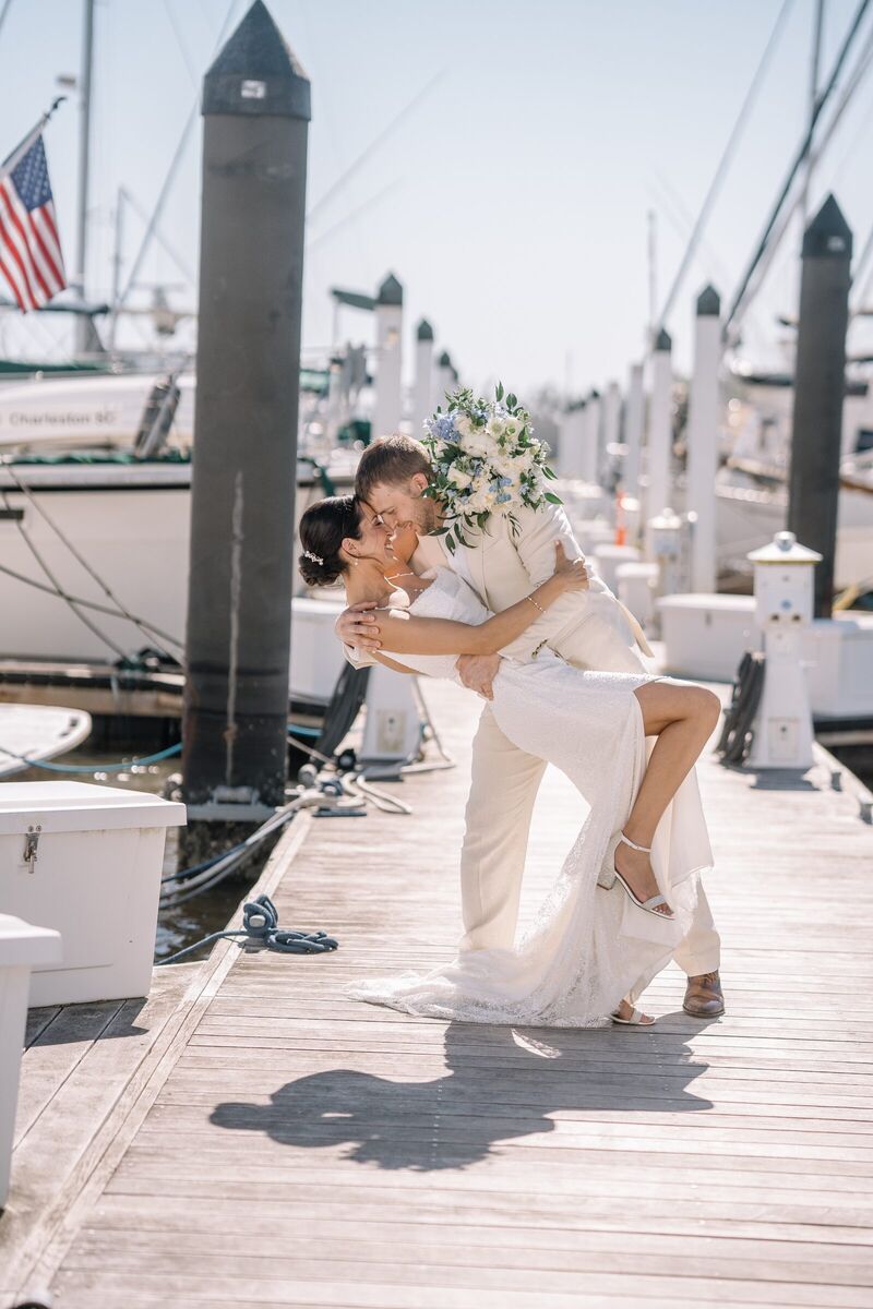 Groom dipping his bride for a kiss on a marina dock