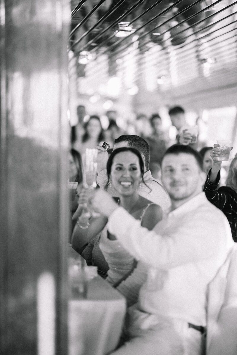 Black and white photo of the bride and groom raising a toast at their reception
